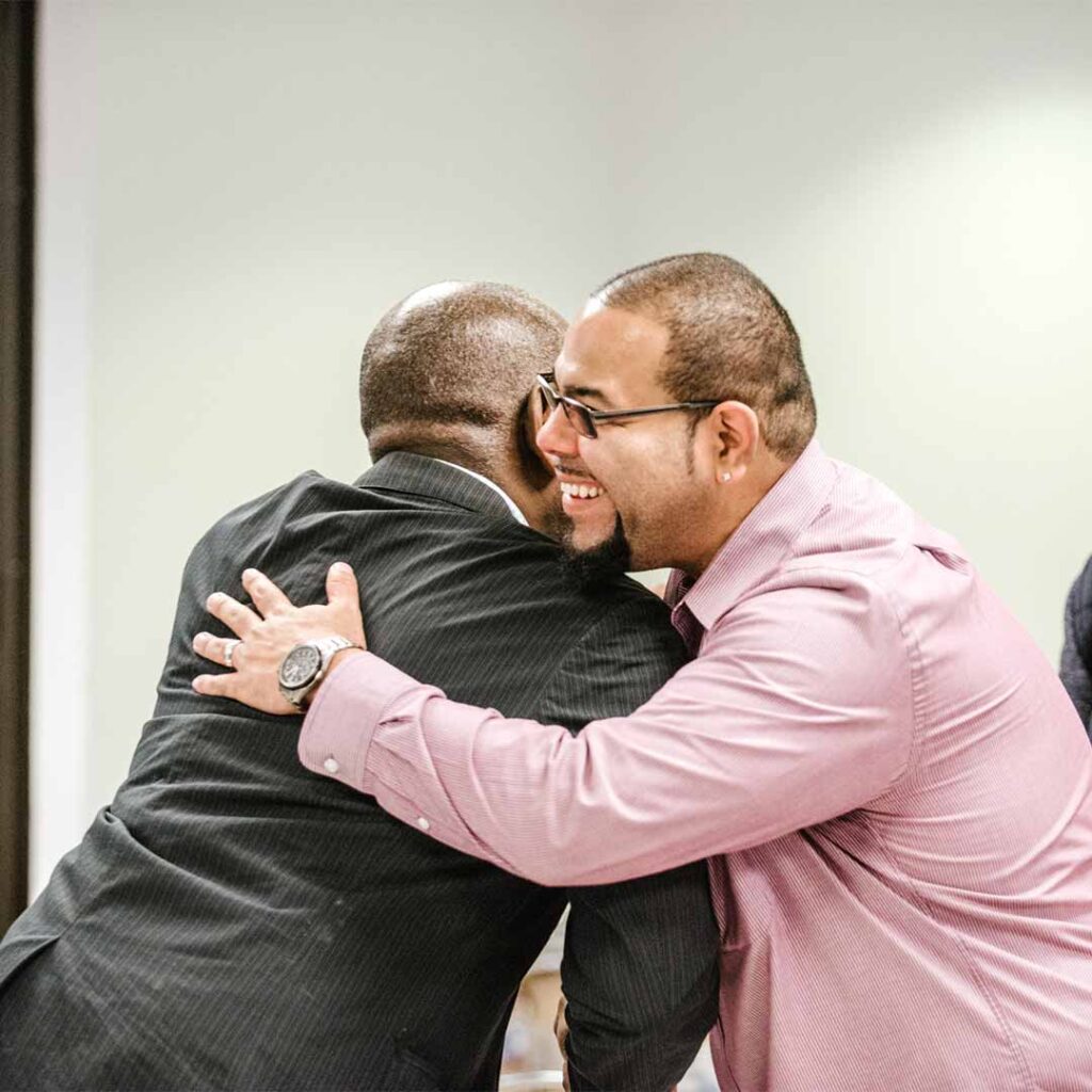 two professional men smiling and hugging