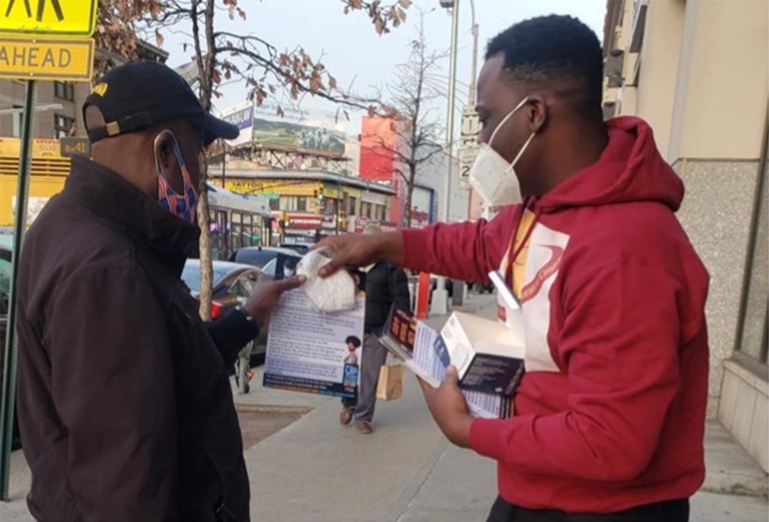 man in new york city handing kn-95 mask and flyer to passersby