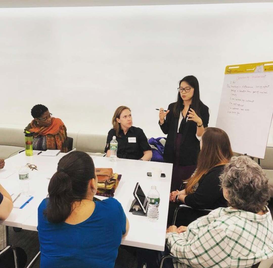 woman at a board holding a meeting with people at a conference