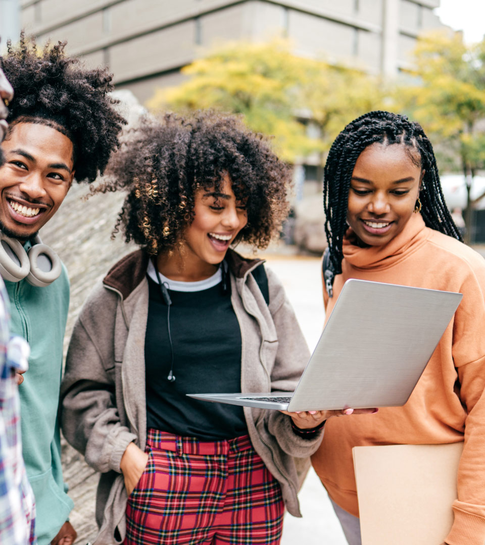 3 happy young people looking at laptop