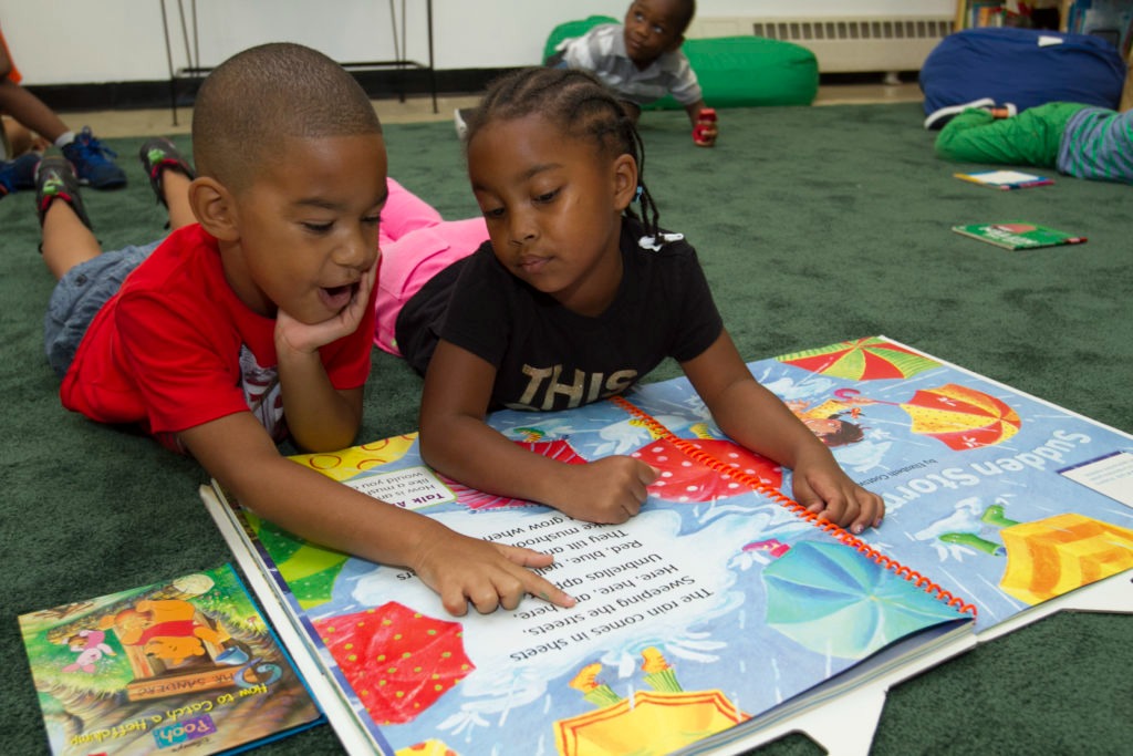 2 children laying on the ground reading